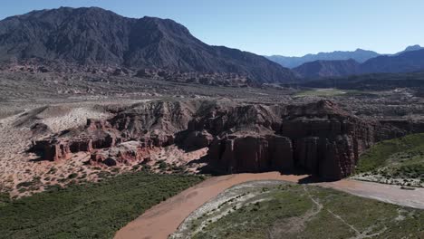 ancient rock solid formation into vineyards, cafayate route in salta argentina, aerial drone fly above mountain range route into subtropical forest, calchaqui valley