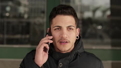 calm young guy with bristle talking on phone and looking at camera