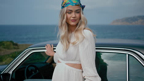 frau in einem vintage-kleid bei einem vintage auto am strand