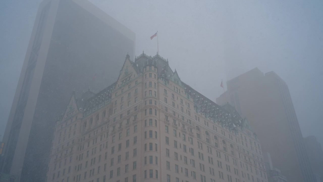 Architectural view of Plaza Hotel during heavy winter snowfall. Low angle view of the Plaza Hotel building in Manhattan enveloped in heavy snow and fog.