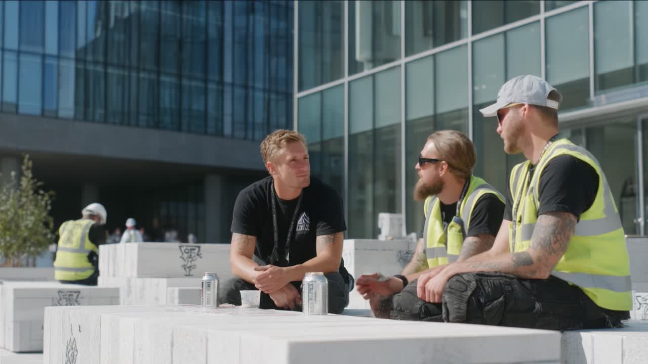 Three Construction Workers Enjoying Their Break in a Modern Urban Setting, Engaging in Conversation While Relaxing on Marble Blocks Under a Bright Sky