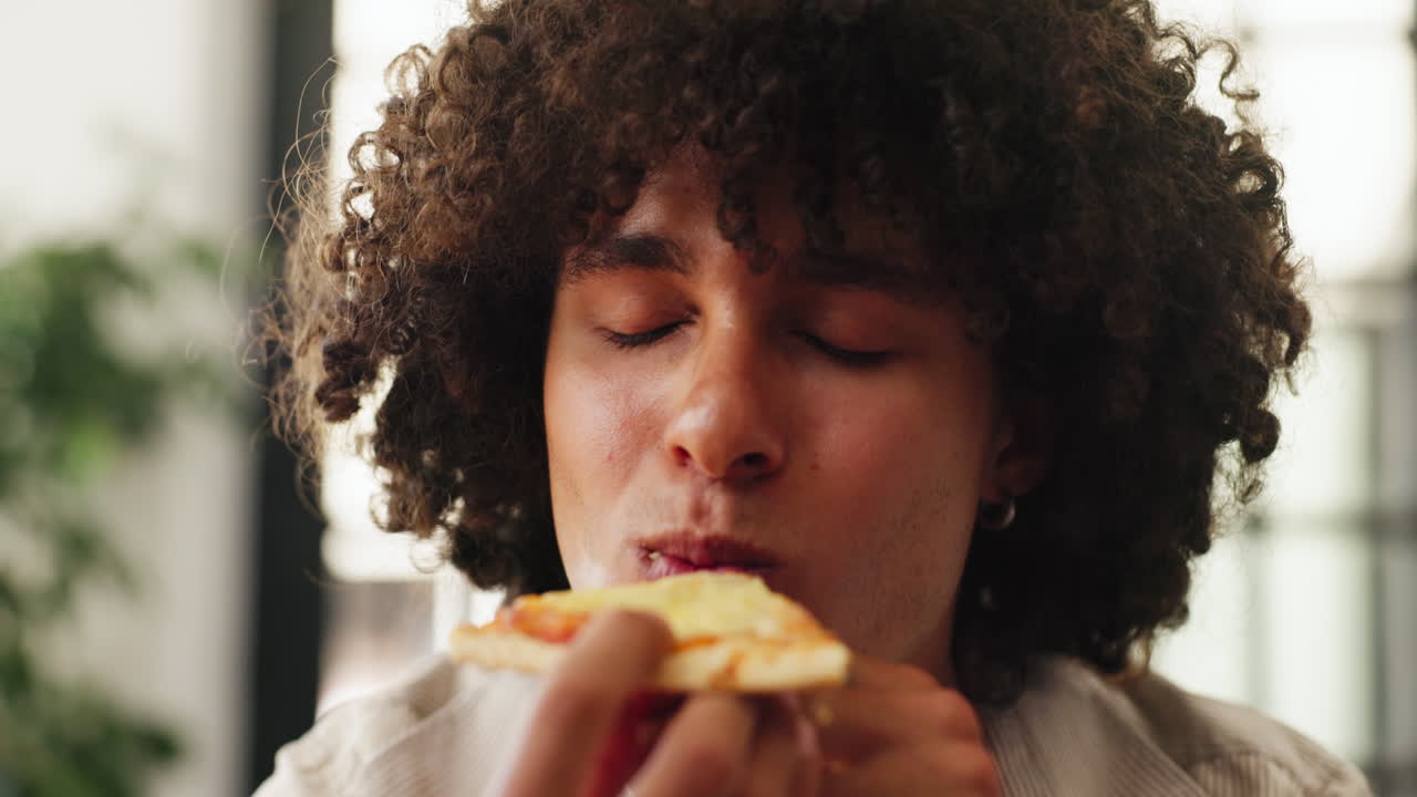 Ung mann nyter et stykke deilig pizza