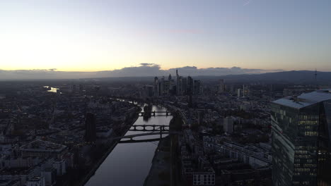 AERIAL:-Establishing-Shot-of-Frankfurt-am-Main,-Germany-Skyline-at-Dusk-Sunset-light-with-European-Central-Bank-and-Downtown-City-Lights