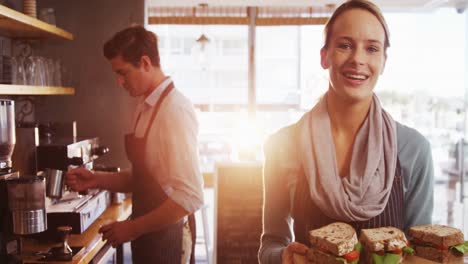 Waitress-holding-a-tray-with-sandwiches-in-cafÃ©