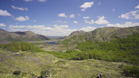 tiro de carro hacia adelante de una persona parada en el borde de una roca con paisajes épicos con cielo maravilloso y nubes en un día soleado en killarney, irlanda en 4k