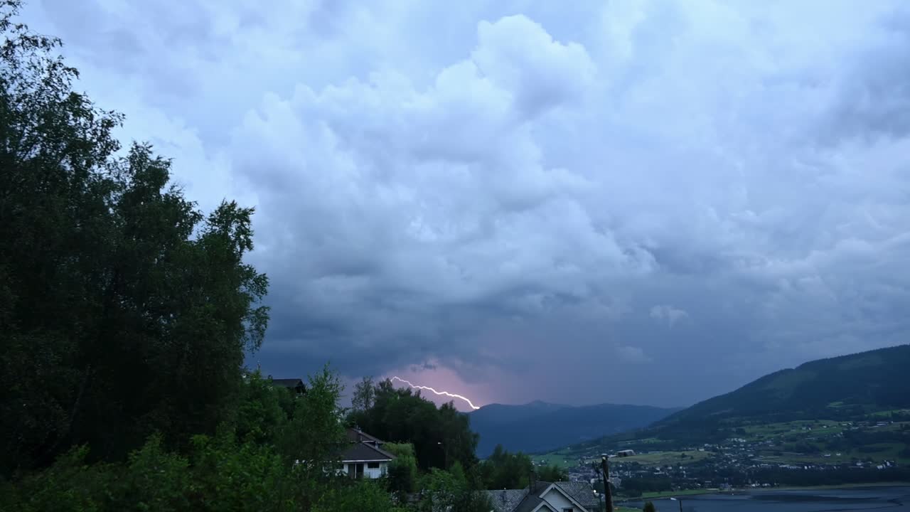 Low angle view of dramatic thunderstorm sky as lightning hits mountain above Voss city in Norway