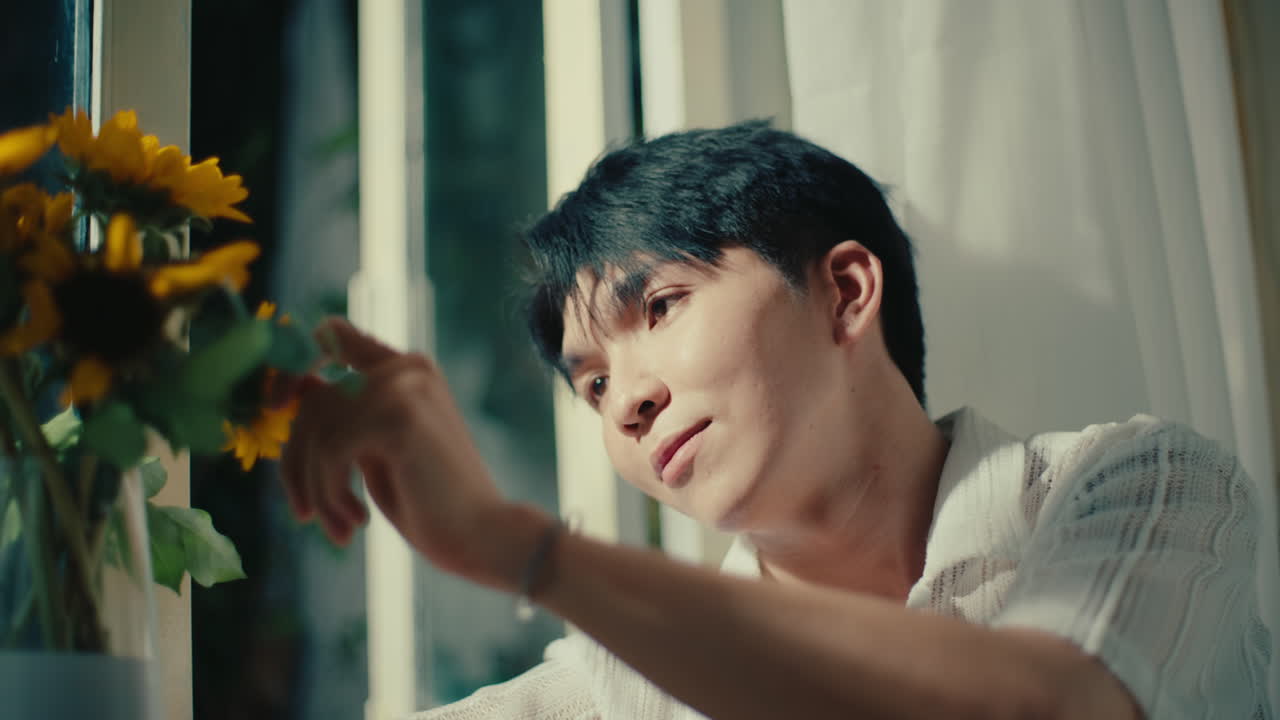 A man looking at sunflowers by the window