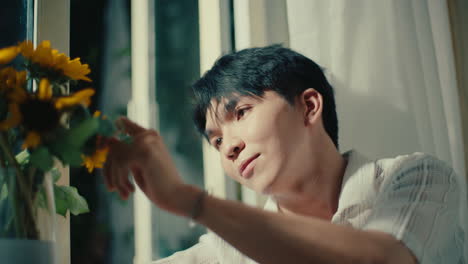 a man looking at sunflowers by the window