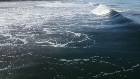 aerial - deep blue ocean swell crashes in front of camera