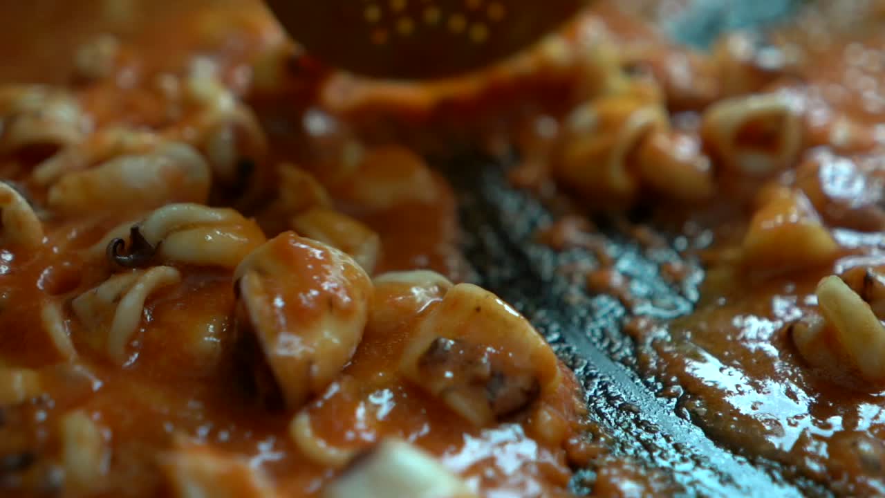 making the sauce with tomato and fideua ingredients on paellon with a kitchen shovel