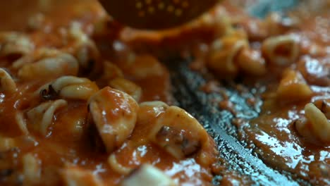 hacer la salsa con ingredientes de tomate y fideuá en paellón con una pala de cocina