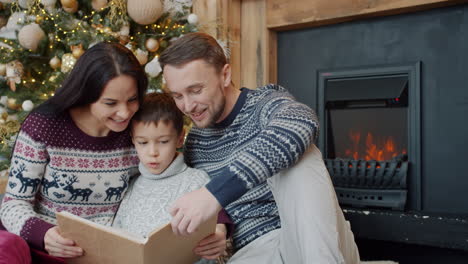 family reading a photo album by the fireplace during christmas