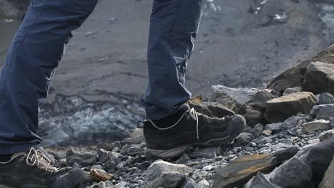 Feet-and-legs-of-a-male-hiker-walking-on-a-stony-path-in-the-Swiss-mountains