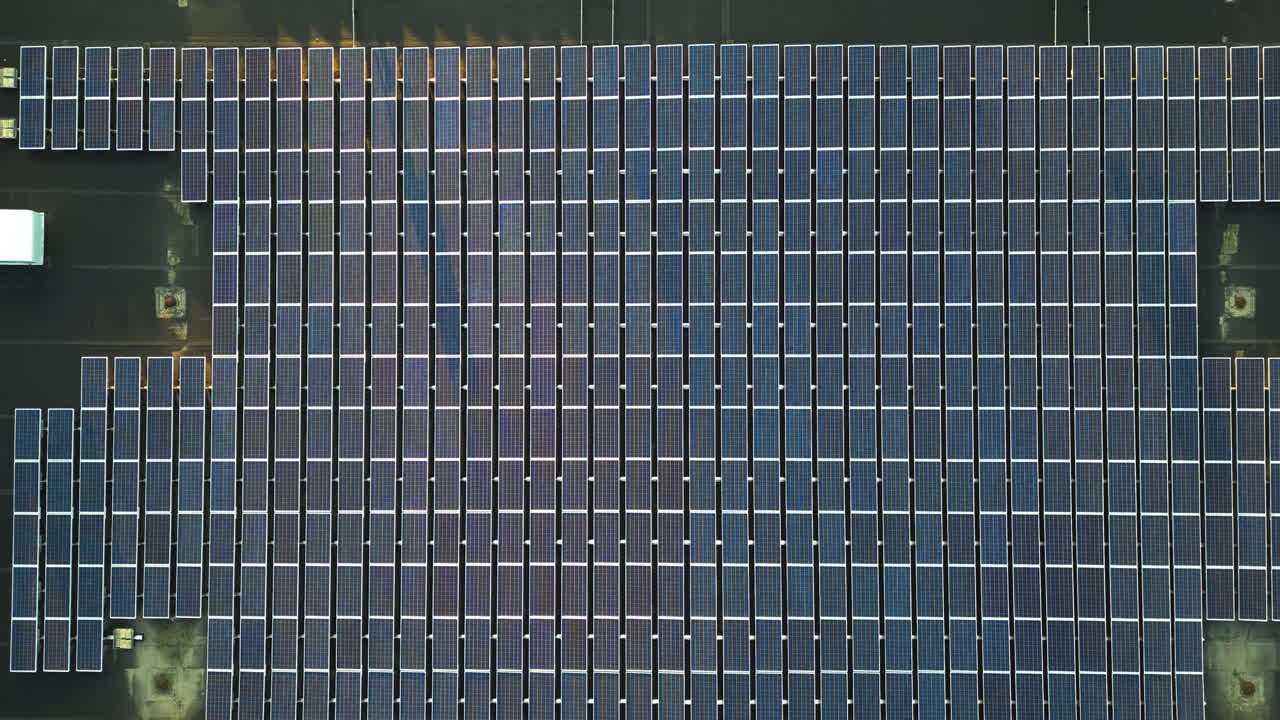 Solar panel farm on roof of building during sunset time. Aerial top down flyover. Alternative energy Production in modern district.