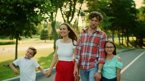 Familia-Feliz-Caminando-Por-La-Calle.-Padres-Alegres-Y-Niños-Tomados-De-La-Mano