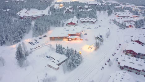 Drohne-Antenne-Nach-Unten-Kippen,-Levi,-Finnland-Mit-Bus-Und-Fußgängern-Auf-Der-Straße-Skidorf