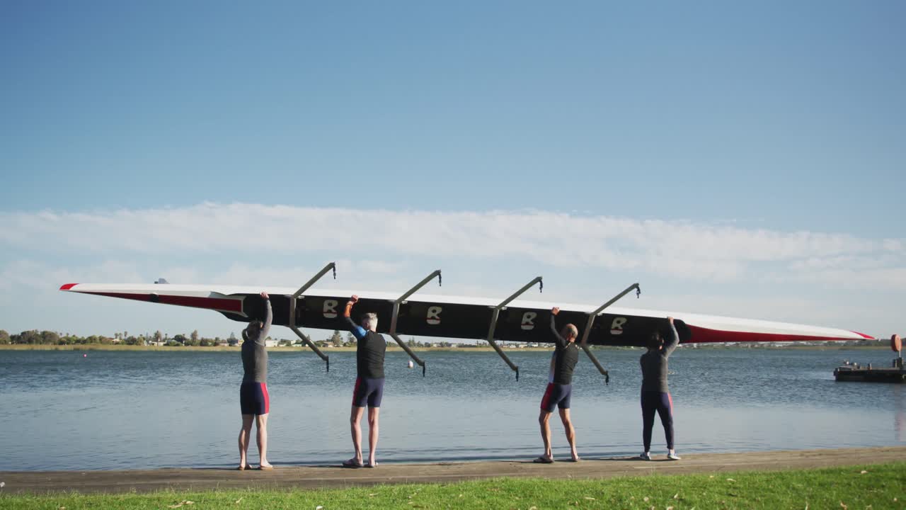 Four senior caucasian men and women carrying a rowing boat together