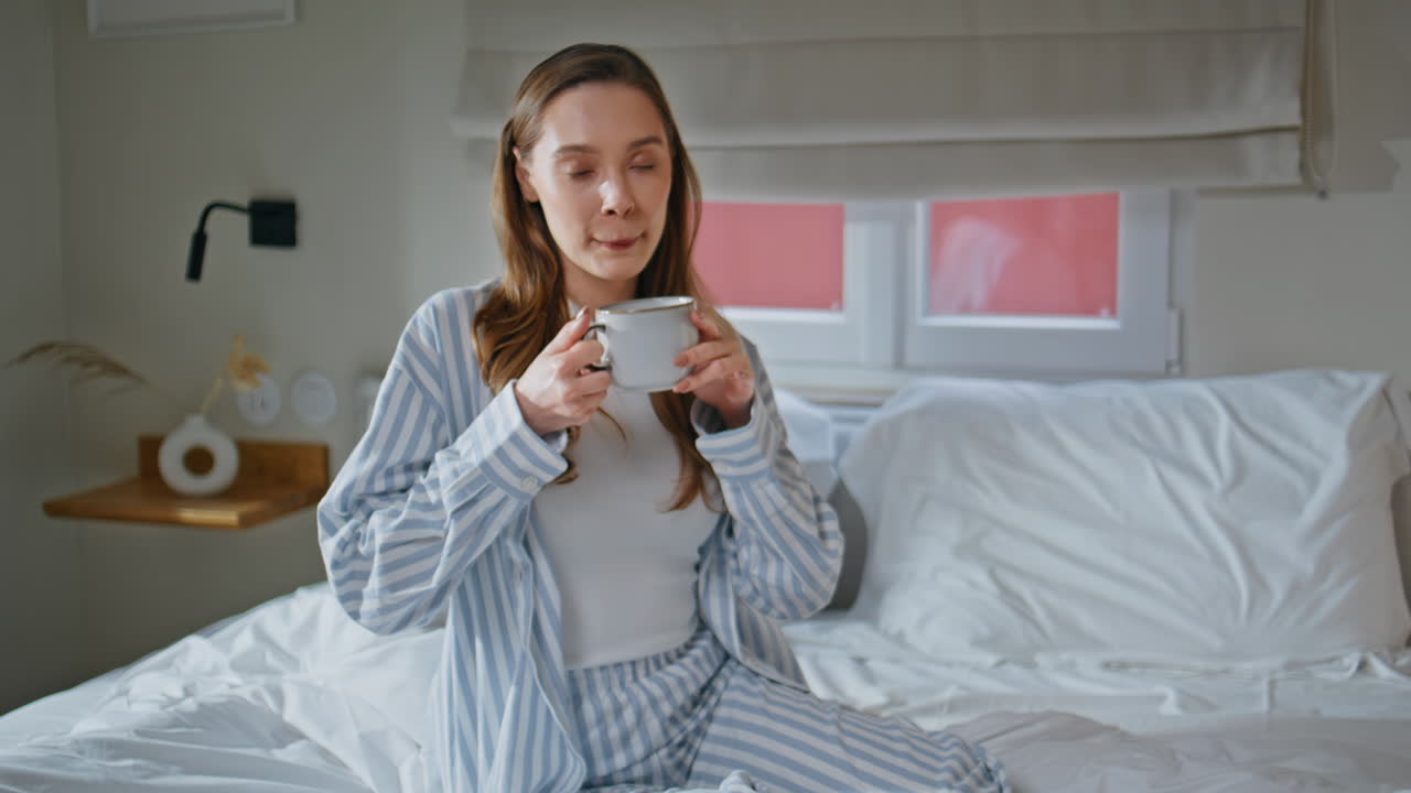 girl tasting coffee relaxing on white bedroom closeup. Woman drinking