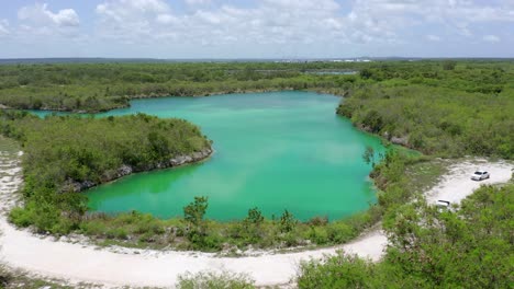 low altitude flight overlooking blue lake in cap cana, turquoise blue waters, two white vans passed on a warm day