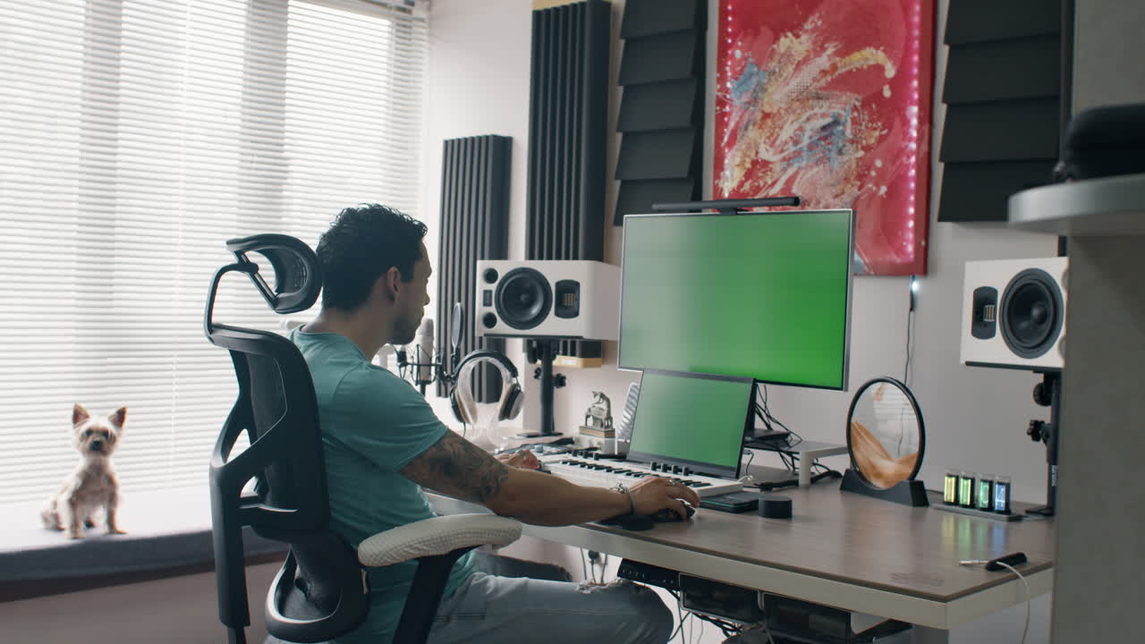 Music producer working at audio workstation in home studio with green screen monitors