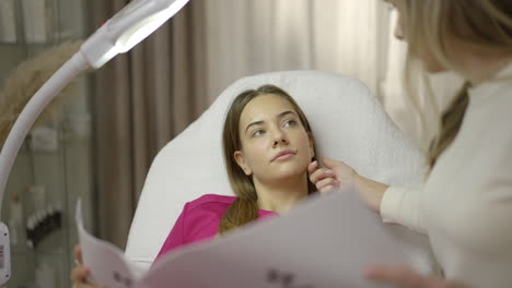 a woman receives a beauty or aesthetic consultation from a professional in a clinic setting