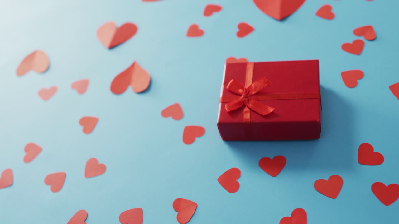 Multiple red paper hearts and red present at valentine's day on blue background