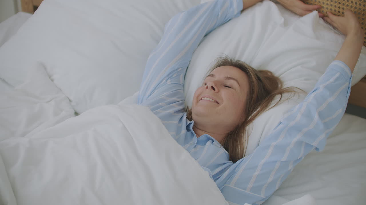 아름다운 여성이 집에서 침대에  ⁇ 어 깨어납니다.