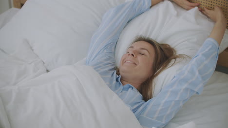 hermosa mujer despertando y estirándose en la cama en casa