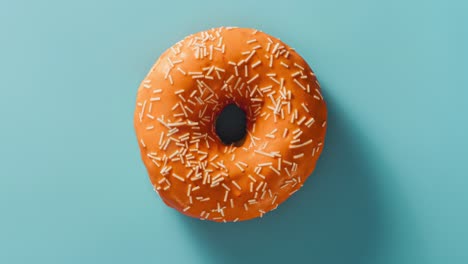 eating glazed donut with sprinkles on blue background. timelapse. 4k, uhd