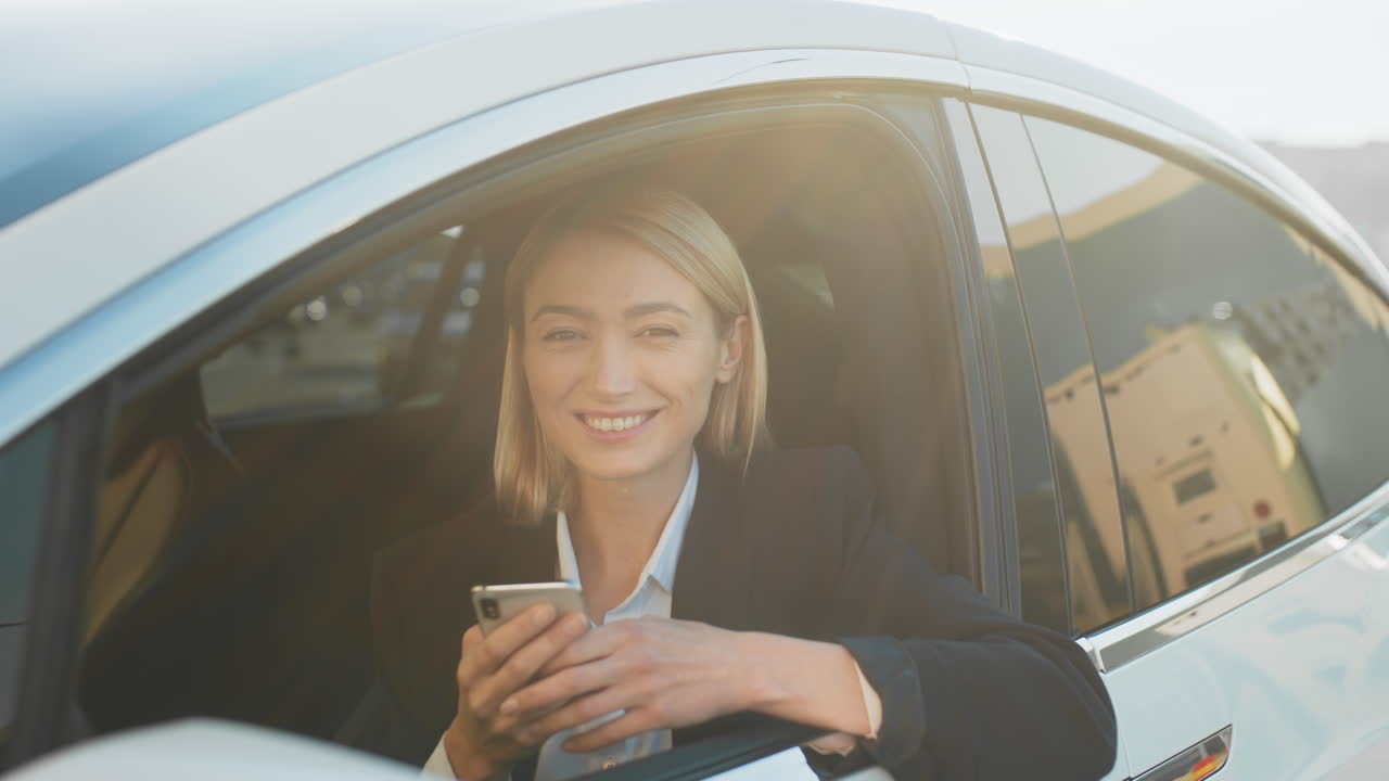 mujer de negocios en un coche eléctrico usando un teléfono inteligente