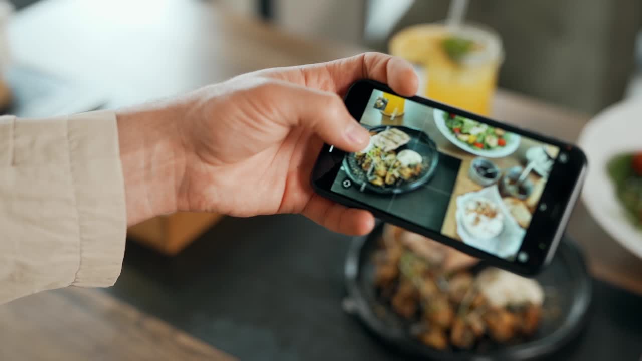 테이블에 스마트폰 음식에 사진을 찍는 남성 손 클로즈업