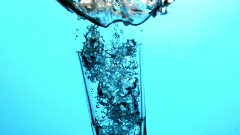 glass falling into blue water