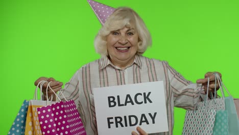 inscription advertising black friday appears next to joyful grandmother with shopping bags