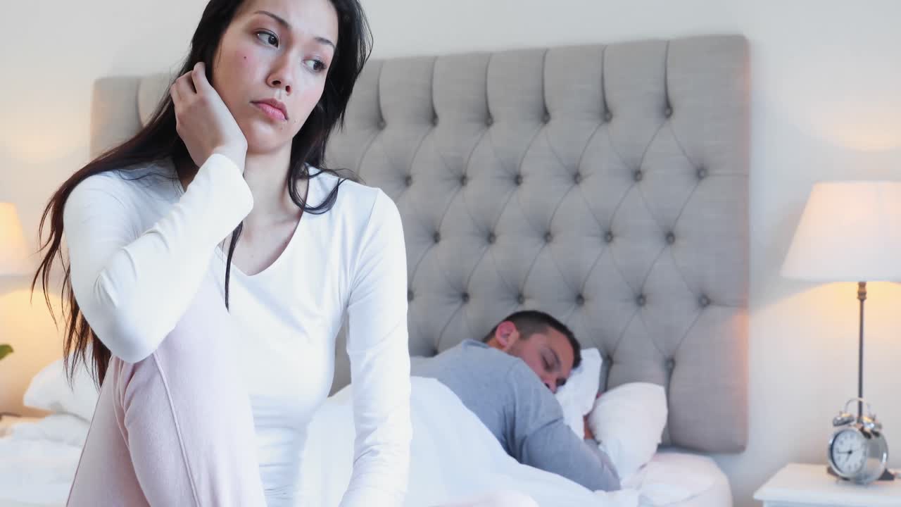 mujer tensa sentada mientras el hombre duerme en la cama 4k