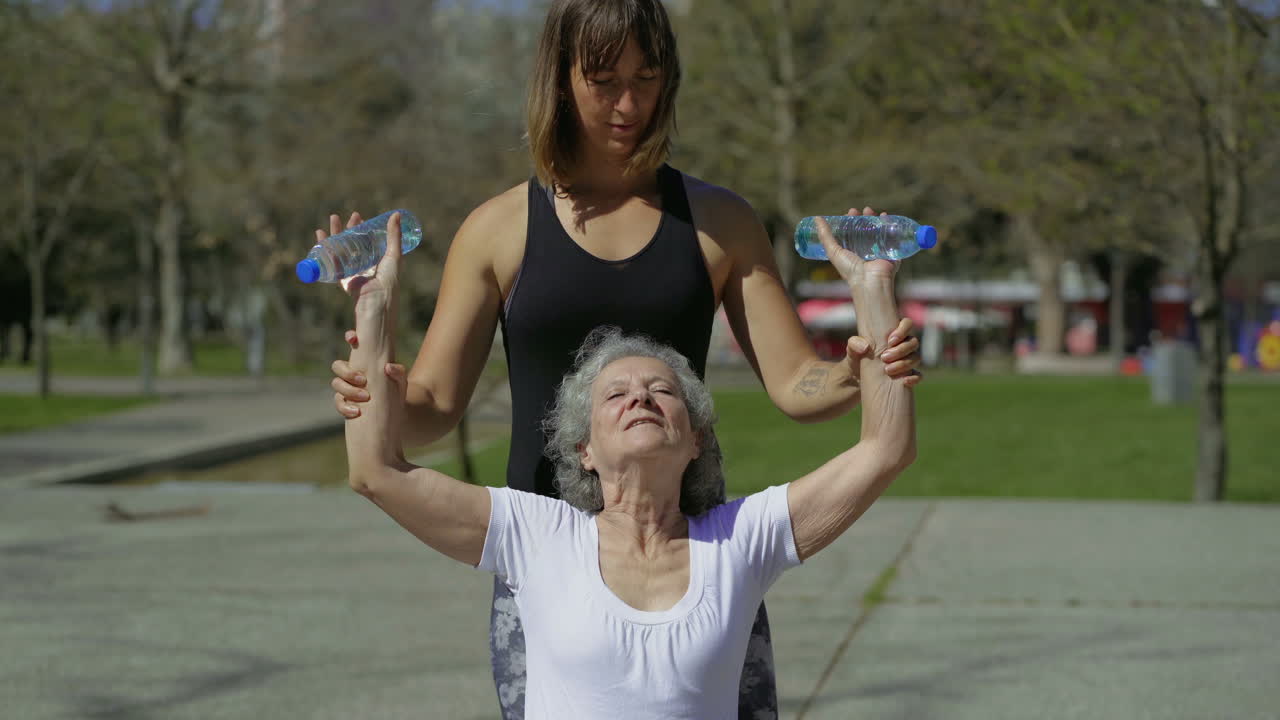 mujer mayor concentrada haciendo ejercicios con el entrenador en el parque.