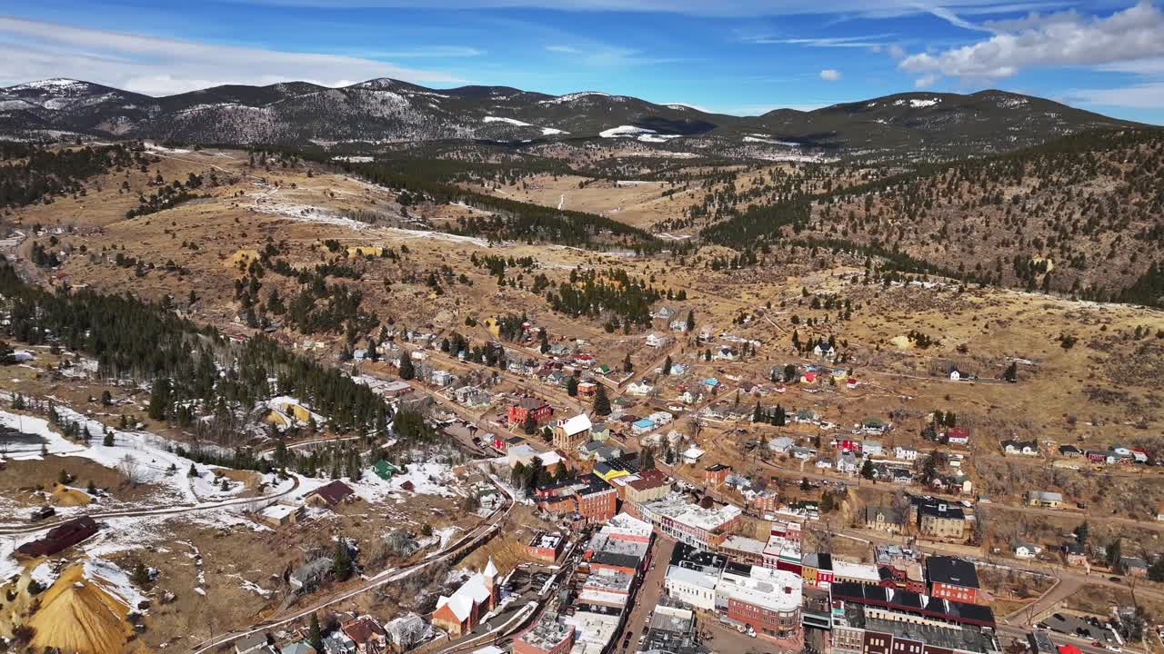 Snowy historic downtown Central City Blackhawk Casino's Idaho Springs sunny blue skies clouds winter day clouds aerial drone Colorado Gilpin County Gold mine Rocky Mountains buildings mountains pan up