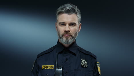 portrait of the handsome young policeman in the uniform looking straight to the camera with serious face