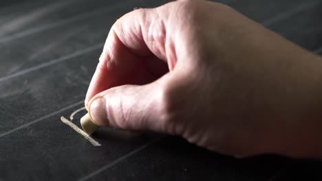 Hands-of-teacher-writing-on-blackboard-with-chalk-close-up-shot