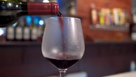 red wine pours into glass, bartender slowly fills wine goblet, slow motion slider -- 4k