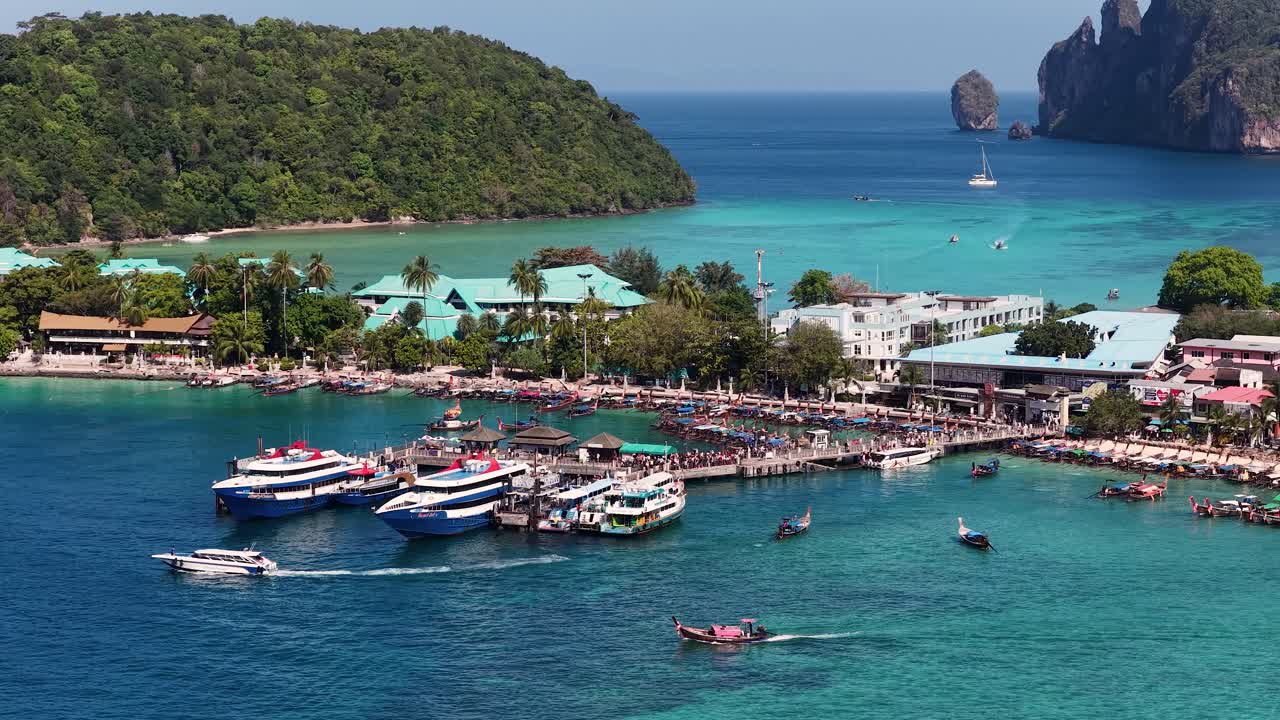 Ampia inquadratura dall'alto di un molo su un'isola tropicale con barche ormeggiate in acqua turchese.