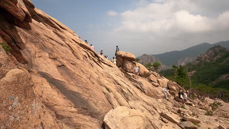 a group of tourists climbing up a rocky slope and enjoying the view from the mountaintop at seoraksan national park in gangwon province, south korea