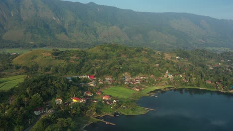 Rotating-aerial-drone-footage-of-lakeside-resort-hotels-and-villages-on-Lake-Toba-in-North-Sumatra,-Indonesia