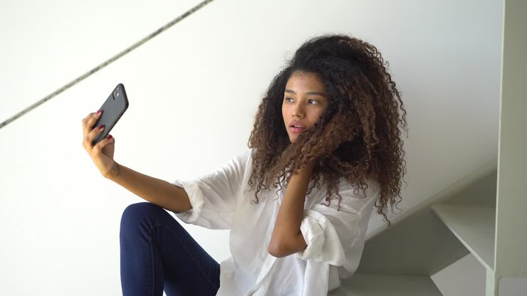 Stylish ethnic woman taking selfie at home