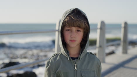 portrait happy caucasian boy enjoying ocean seaside wearing jacket on windy sunny day slow motion