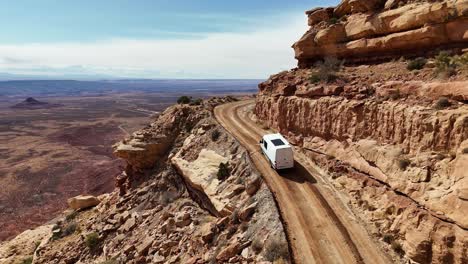 camper van driving on the edge of a cliff going up a mountain, the moki dugway near mexican hat, utah, drone view