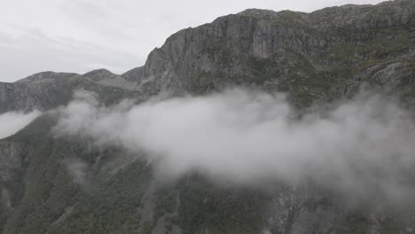 massive rocky mountain standing above cloudscape, high altitude drone shot
