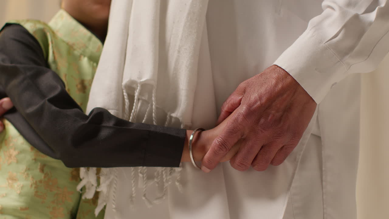 젊은 시크 소년의 클로즈업 스튜디오 은 단 이 인 바지를 입고 평평한 배경에 할아버지를 포옹하고 있습니다.