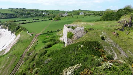 abandoned overgrown ivy covered desolate countryside historical welsh coastal brick factory mill aerial view push in left to front shot