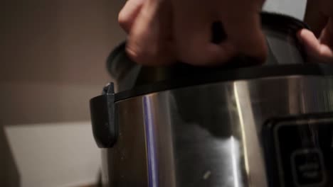 close-up view of hands opening and lifting rice pot out of multi-function pressure cooker