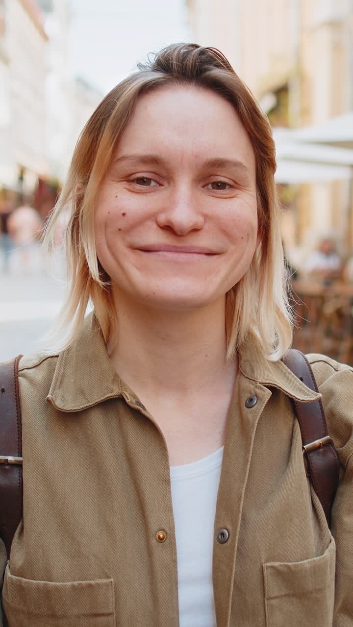 Ritratto di una giovane donna felice e sorridente che guarda la telecamera che riposa all'aperto in una strada della città